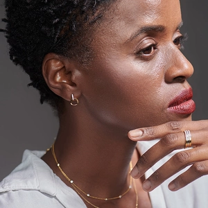 Close-up of gold stud earrings and matching jewelry set on a model with elegant styling