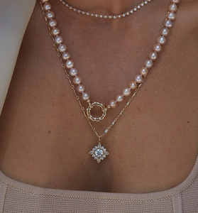 Close-up of triple-layered gold necklace with pearls and sparkling starburst pendant