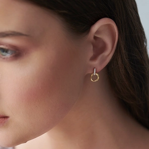 Macro shot of elegant two-tone hoop earrings with pavé diamonds on a female model
