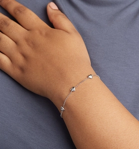 Gros plan de charms en cœur avec zircons sur un bracelet délicat en argent sterling S925