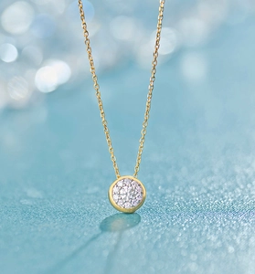 Macro shot of S925 silver round zircon pendant with gold chain on blue bokeh background