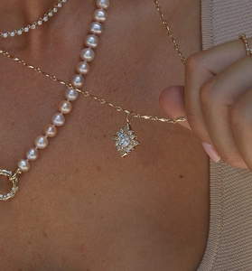 Detailed close-up of a layered gold necklace set with pearls and a sparkling star pendant
