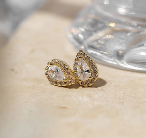 Macro view of pear-cut zircon earrings with gold plating and halo setting details