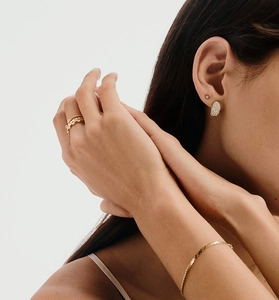 Detail showing elegant gold jewelry set with sparkling zircon rings and curved earrings