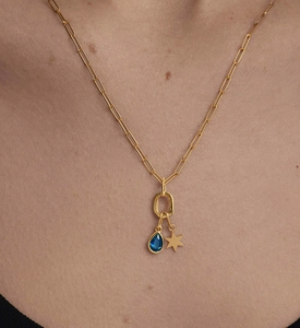 Close-up of golden paperclip chain necklace with blue teardrop and star pendant