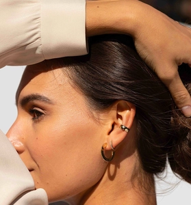 Close-up of golden S925 silver hoop earrings and sparkling ear cuff on a model