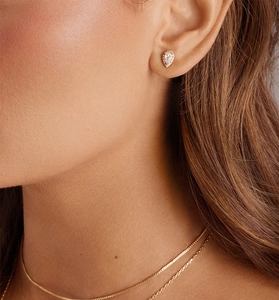 Close-up of gold pear-cut cubic zirconia halo stud earring worn on model ear