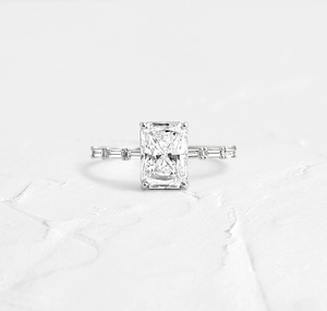 Close-up of S925 sterling silver ring with emerald cut zircon stone on white stone surface