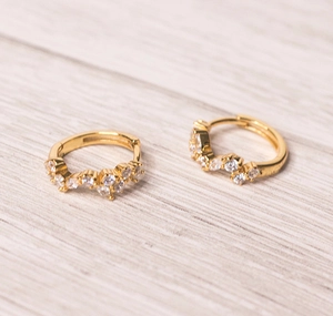 Macro shot of gold-plated huggie earrings with marquise and round zircon inlay details