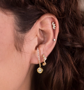 Close-up of gold-plated irregular zircon earrings and leaf-shaped ear cuff on model