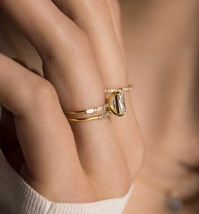Macro view of stacked gold rings featuring emerald cut zircon and pave diamonds