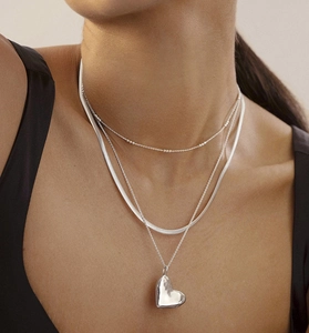 Close-up of layered S925 sterling silver necklaces with heart pendant on model
