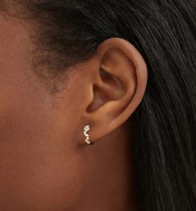 Close-up of gold irregular curved ear cuff with paved zircon stones on model
