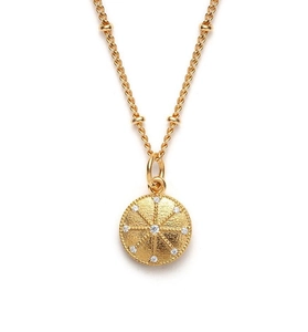 Macro shot of gold starburst pendant with textured finish and zircon accents