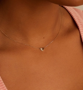 Detail of S925 silver heart necklace with pavé stones and rose gold finish on a model