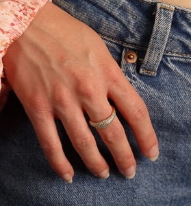Close-up of sparkling cubic zirconia gold ring worn by a model in casual denim outfit
