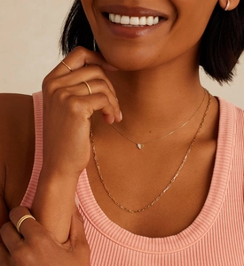 Close-up of minimalist layered gold necklaces with small heart pendant and paperclip chain