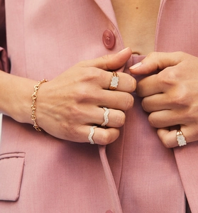 Close-up of a model wearing a set of gold-plated rings and a chain bracelet with diamonds