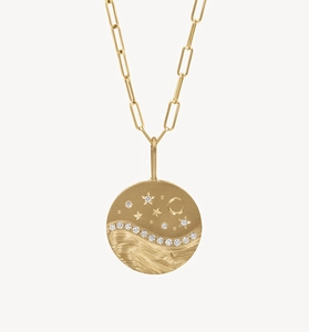 Detailed close-up of gold moon and stars pendant with sparkling wave pattern and paperclip chain