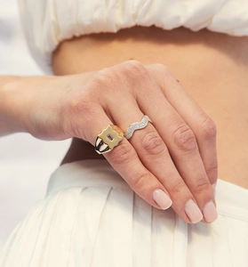 Detail of stacked gold signet ring with purple stone and silver wavy diamond band