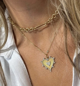 Detail of layered gold choker and heart pendant necklace with shimmering zircon stones