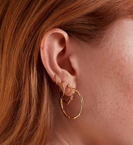 Macro detail of gold textured hoop earrings showing lava surface on three sizes