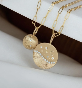 Macro detail of gold paperclip chain and star moon engraved pendants with pavé diamonds
