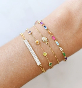 Macro view of gold bracelets set with colorful gemstones and ladybird charm