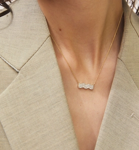 Vue rapprochée d'un collier doré avec pendentif rectangulaire ondulé et zircons brillants