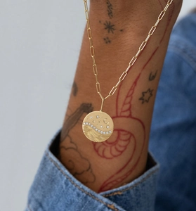Detail of gold star and moon pendant with pavé diamonds on a paperclip chain necklace