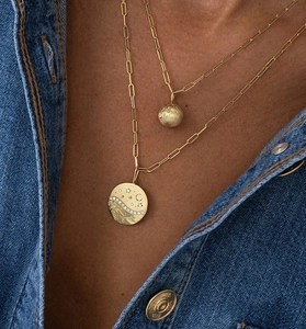 Macro detail of layered gold necklaces with celestial star and moon engraved pendants