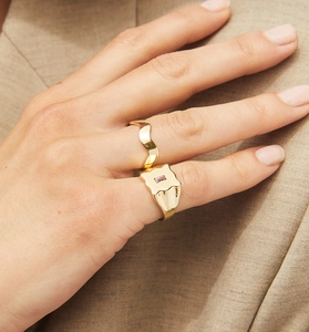 Close-up of gold irregular signet ring with purple gemstone and a wavy gold band