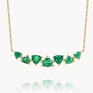 Elegant gold necklace with seven vibrant green triangle-cut stones in curved setting