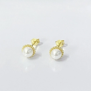 Macro detail of S925 silver pearl stud earrings with golden beaded base and butterfly backs