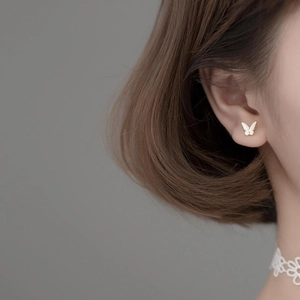 Exquisite gold butterfly stud earrings with white enamel finish on female model ear