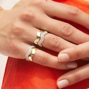Stackable S925 sterling silver wavy rings with pavé cubic zirconia on an orange background