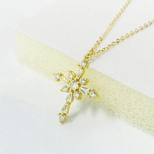 Vue macro du pendentif croix dorée avec zircons transparents sur une chaîne fine