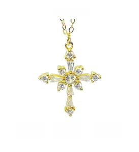 Vue détaillée du pendentif croix dorée serti de zircons blancs sur fond blanc épuré