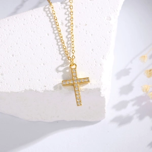 Elegant gold cross pendant necklace with sparkling micro-set cubic zirconia on white stone