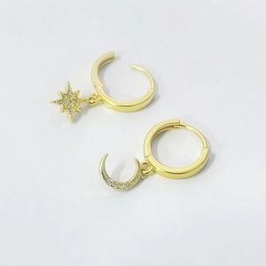 Detail view of gold hoop earrings with sparkling zircon star and moon charms