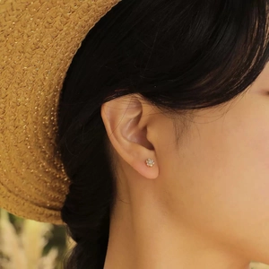 Elegant gold flower stud earrings with sparkling crystals worn for a summer vacation look