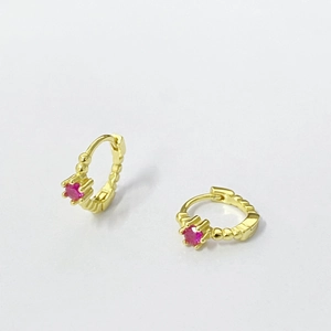 Boucles d'oreilles créoles dorées avec zircon rouge et texture perlée sur blanc