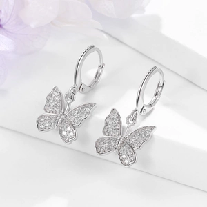 Macro shot of silver butterfly hoop earrings with sparkling cubic zirconia on a white stand