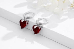 Détail macro des boucles d'oreilles flèche de Cupidon en argent 925 et zircon rouge