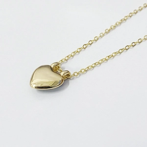 Détail du pendentif cœur 3D doré avec finition miroir polie et fine chaîne délicate