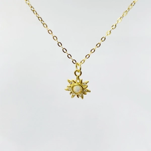 Macro detail of sunburst opal pendant necklace in gold with shimmering cubic zirconia
