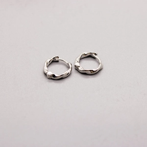 Macro detail of twisted texture on minimalist S925 sterling silver hoop earrings