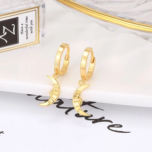Baroque style gold moon face pendant earrings showcased in a luxury still life setting