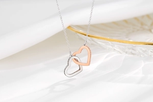 Close-up of interlocking silver and rose gold hearts with zircons on a delicate chain