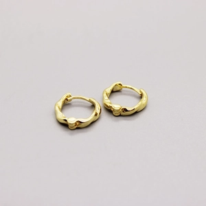 Macro detail of gold plated S925 sterling silver hoop earrings with twisted metal texture